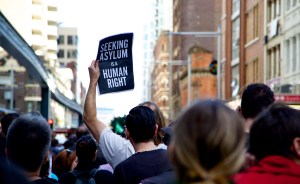 Protester holding sign sayin "seeking asylum is a human right"